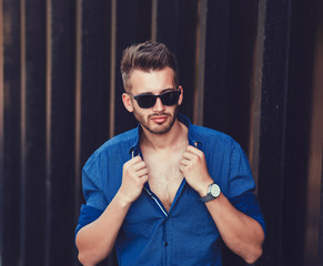 Obraz premium Handsome man in shirt and stylish sunglasses posing in city
