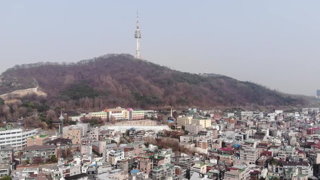 Mixed low-rise buildings at bottom of Nam mountain, aerial panorama of Huam-dong at Seoul city. Television tower seen on top of mount. Old houses on foreground
