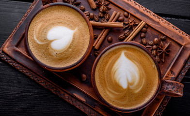 Two cups of cappuccino coffee with latte art on dark background