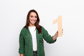 young pretty woman excited, happy, joyful, holding a number 1.