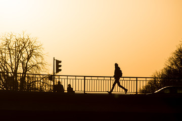  silhouette of man running on the bridge by sunset