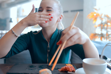 girl eats sushi and rolls in a restaurant / oriental cuisine, Japanese food, young model in a...