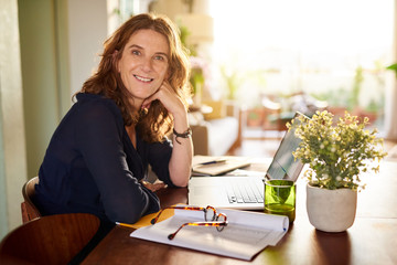 Mature female entrepreneur smiling while working from home