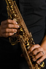 soprano saxophone in hands on a black background
