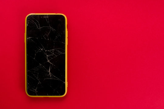 Smartphone with broken screen on red background