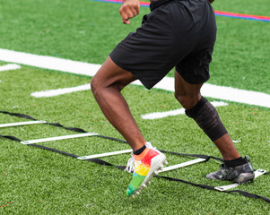 Athlete running ladder drills on turf field in cleats