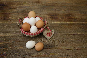 Organic eggs in a basket with a decorated checkered napkin and a heart made of linen fabric on a wooden rustic background with copy space for text. Farm products. Easter holiday.