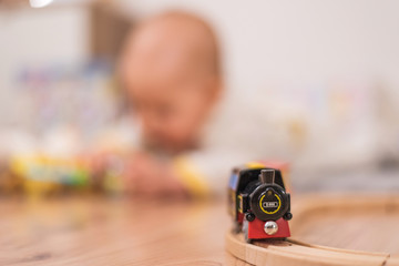 Baby is playing on the floor with toys and small train arrives
