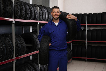 Fototapeta na wymiar Male mechanic with car tires in auto store