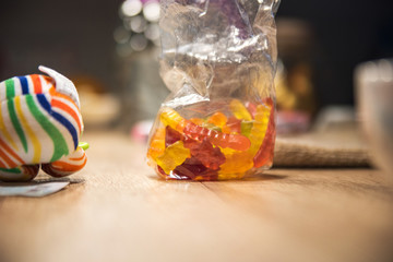Colorful candy on wooden table in dark room with toys