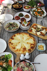 Khachapuri in ajarian. Georgian national cuisine, .dining table on a wooden board with fresh vegetables and herbs