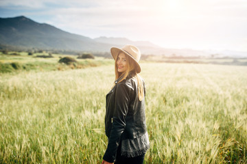 Naklejka na ściany i meble Beautiful smiling girl in a hat on a green field