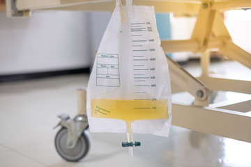 Urine bag hanging under patient bed in room at hospital.