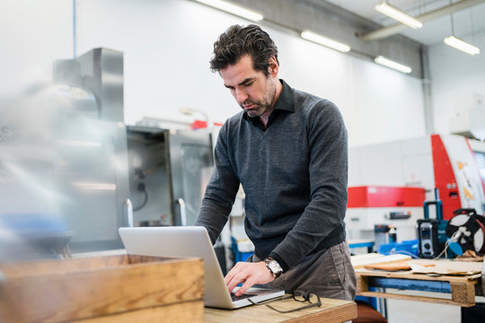 Businessman Using Laptop In A Factory