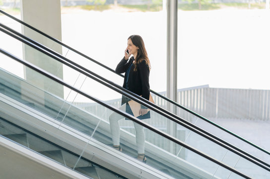 Smiling businesswoman on escalator talking on the phone