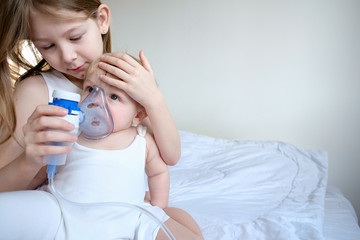 The children got sick. The older sister takes care of her brother and holds a gmu mask for...