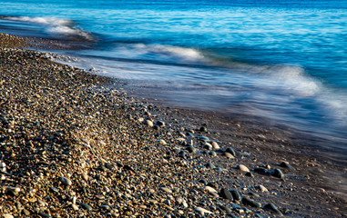 Stormy Sky and Wavy Ocean with waves hitting the seashore full with beautiful pebbles.
