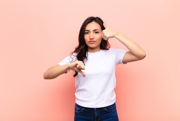 young latin pretty woman feeling confused, clueless and unsure, weighting the good and bad in...