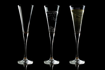 Sparkling wine glasses with bubbles on black background with reflection.