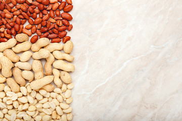 Frame made of mix nuts peanuts in shell and peeled peanuts with copy space on white marble...