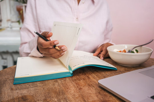 Close-up of young woman taking notes at table
