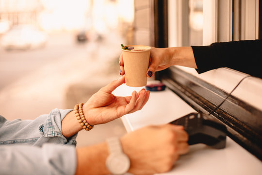 Female barista giving coffee to customer while he making payment