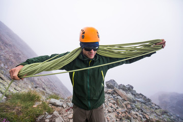 Climber coils climbing rope after rappel.