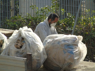Operaio con mascherina smaltisce materie di scarto in cantiere