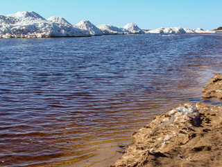 landscape with blue sea, sandy shore and white ice cubes, sunny spring day, Baltic Sea, in Latvia