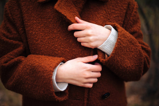 Unrecognizable  female hands in bright  brown coat in autumn
