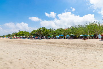 KUTA, BALI / INDONESIA - NOVEMBER 8, 2019: Kuta beach in Bali. Wide sandy beach with many sunbeds and umbrellas. Best place for surfing.