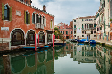 A beautiful photo of the canals of Venice through which gondolas walk and carry tourists