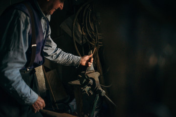 Old man working in the retro blacksmith.