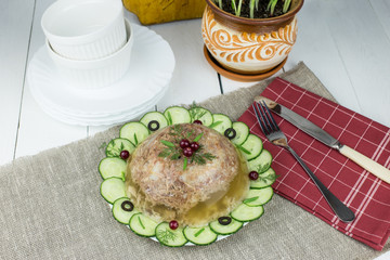 National Russian traditional dish - jelly. Homemade aspic with meat and spices, decorated with cucumbers, berries and green onions.