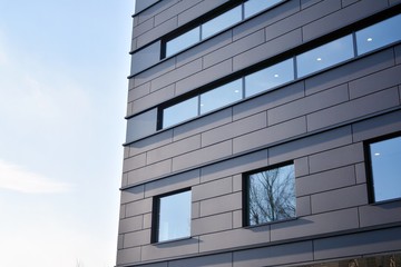 A view at a straight facade of a modern building with a dark grey facade.