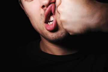 Strong fist punching the face of young angry Caucasian man