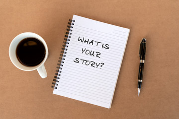 What is your story ? text on note pad on top of wood desk