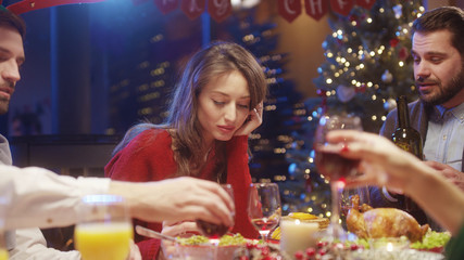 Young upset woman contemplating sitting in despair on noel evening. Frustrated sad girl gathering with friends for Christmas holiday dinner celebration.