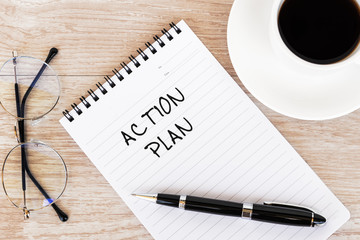 Action Plan text on note pad on top of wood desk