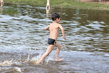 the boy runs through the water splashing drops of water