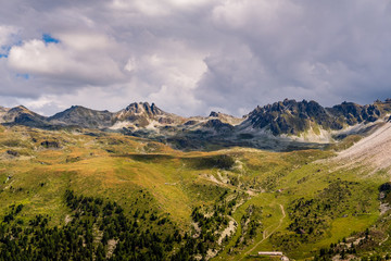 Fototapeta premium Rock formation and alpine pastures high up in the Pennine Alps above Saint-Luc under dramatic clouds in summer. Anniviers, Valais, Switzerland