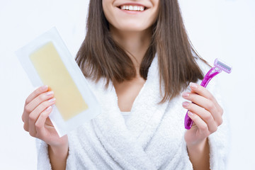 Portrait of young woman is choosing unwanted hair removal tool. Girl is holding  disposable razor and wax stripe, going to shave depilate legs, armpits, bikini zone. Personal care and hygiene product