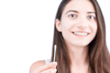 Young smiling woman is holding in hand disposable cotton bud, swab, stick. Girl is going to clean her auricle. Personal hygiene and care product concept. Prevention of ear diseases. Earwax removal.