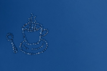 Classic blue background. Cup and spoon of coffee beans. Space for text.  Stylish toning color 2020. The view from the top. Mockup