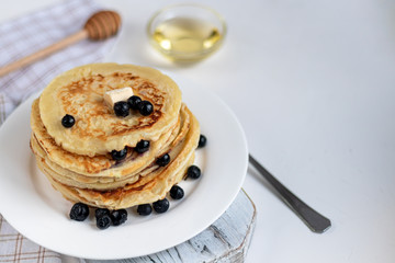 A stack of delicious pancakes with raspberries, blackberries and blueberries. On a light background. Sprinkled with icing sugar and decorated