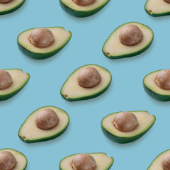 Avocado half pattern on blue background. Vegan food ingredient