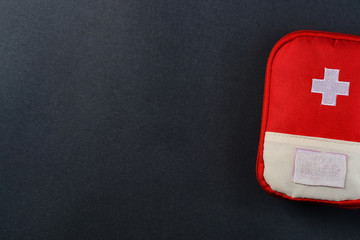 Closed red travel first aid kit pouch on the dark background. Photo with a copy space