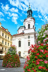 Fototapeta na wymiar Prague in Summer with beautiful red and white flower arrangements by St. Nikolas Church at Stare Mesto or Old Market Square in Prague, Czech Republic in Summer