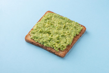 Toast with mashed avocado on blue background