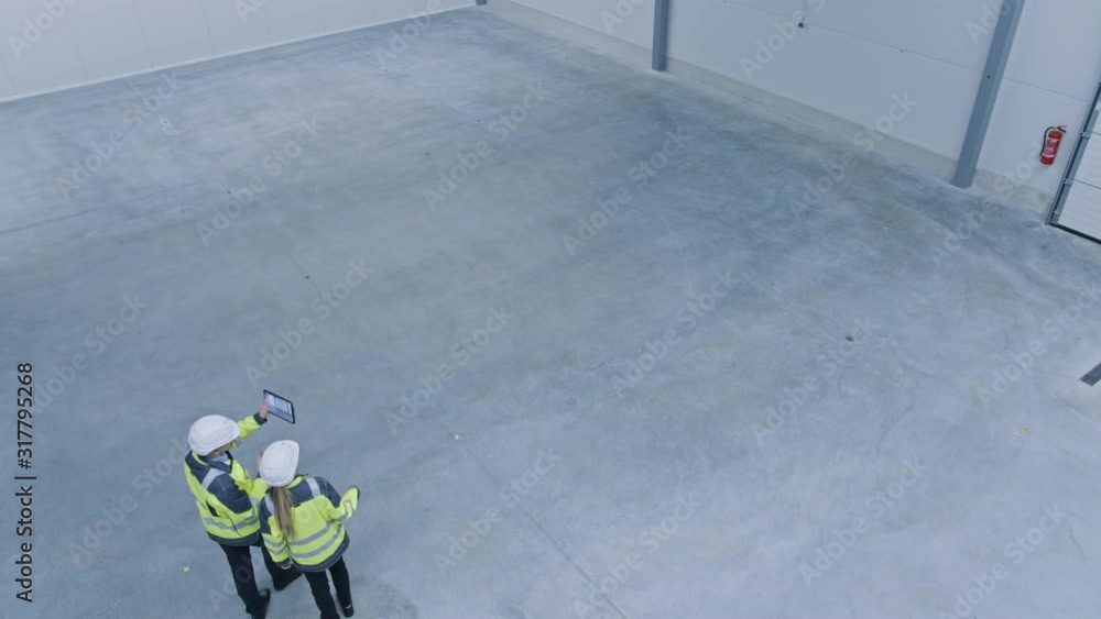 Aufkleber two engineers talking, walking across empty factory floor, inspecting, planning where all the machin